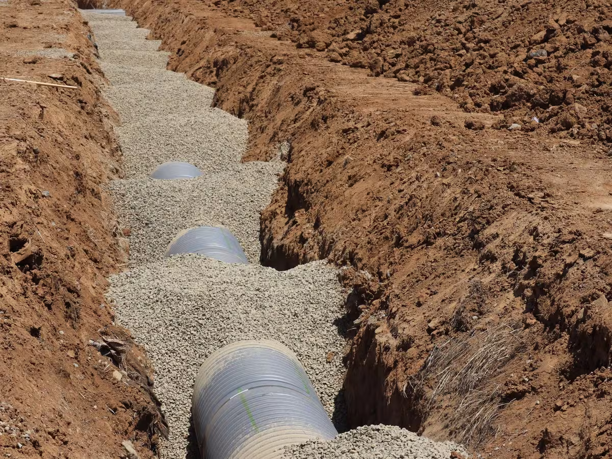 Drain field pipe bedded in gravel before backfilling