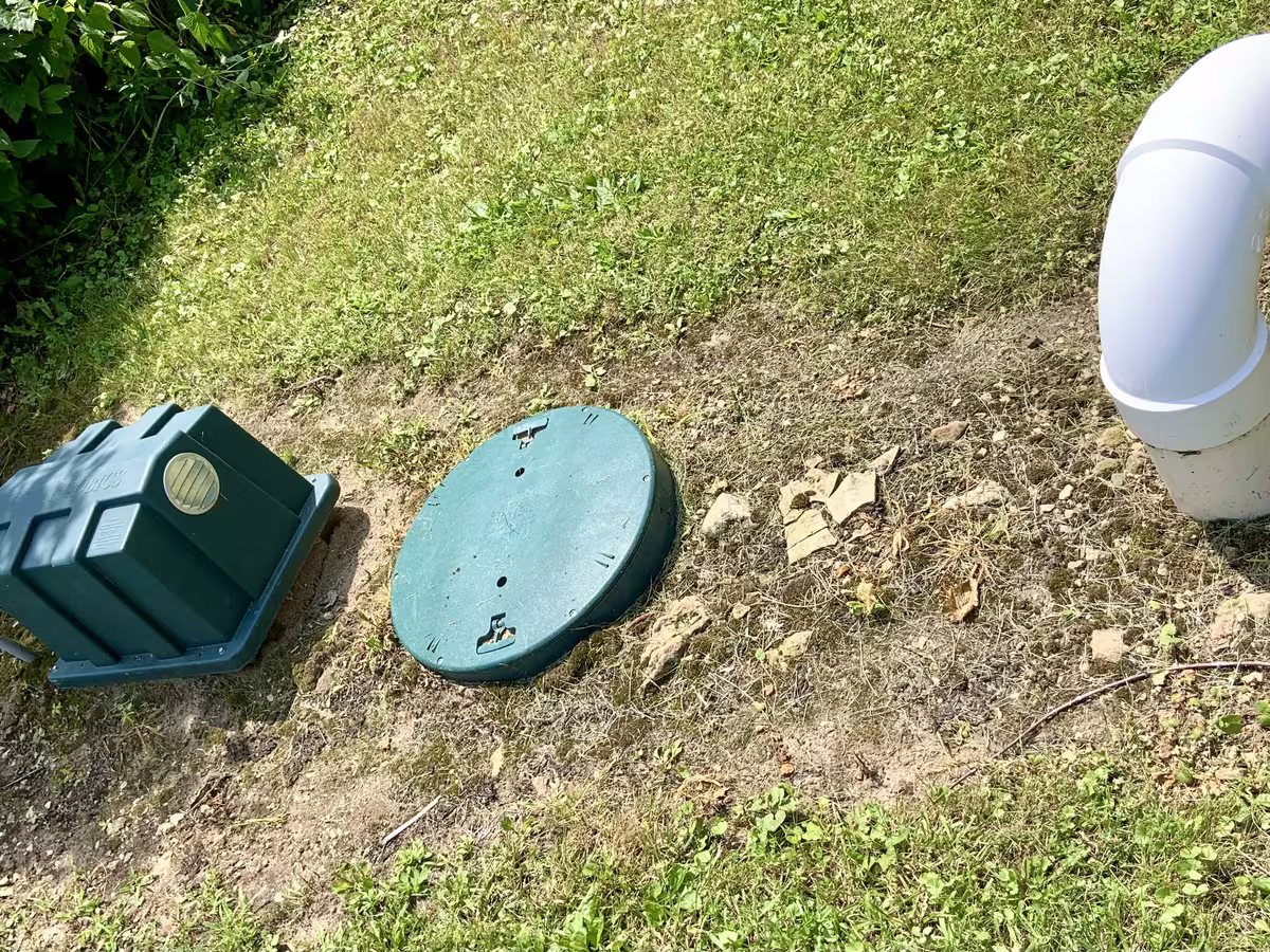 A septic riser lid, pump housing and vent pipe set level with the lawn